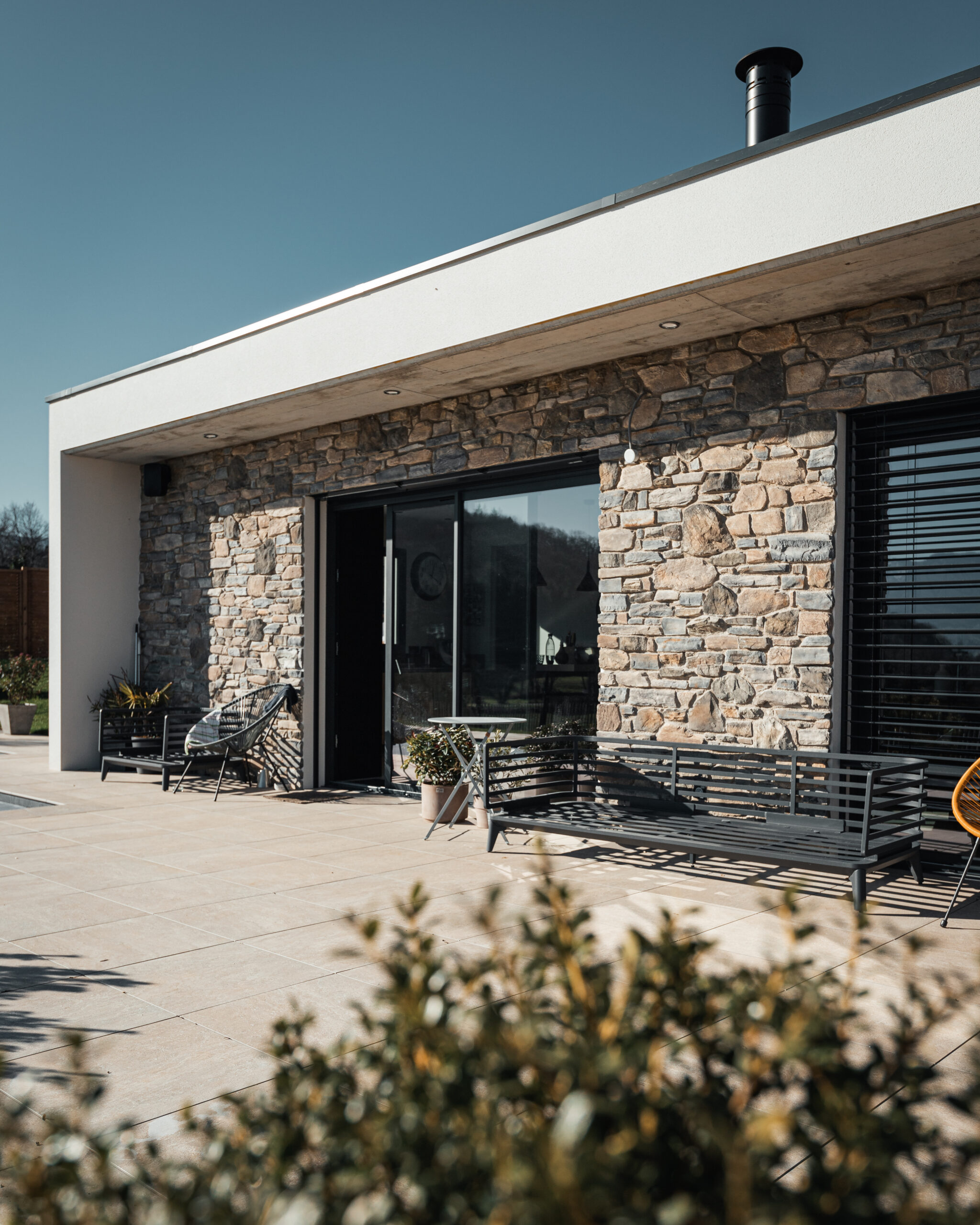 Terrasse extérieur d'une maison moderne et contemporaine au toit plat, construite à Saint Alban Leysse en Savoie.