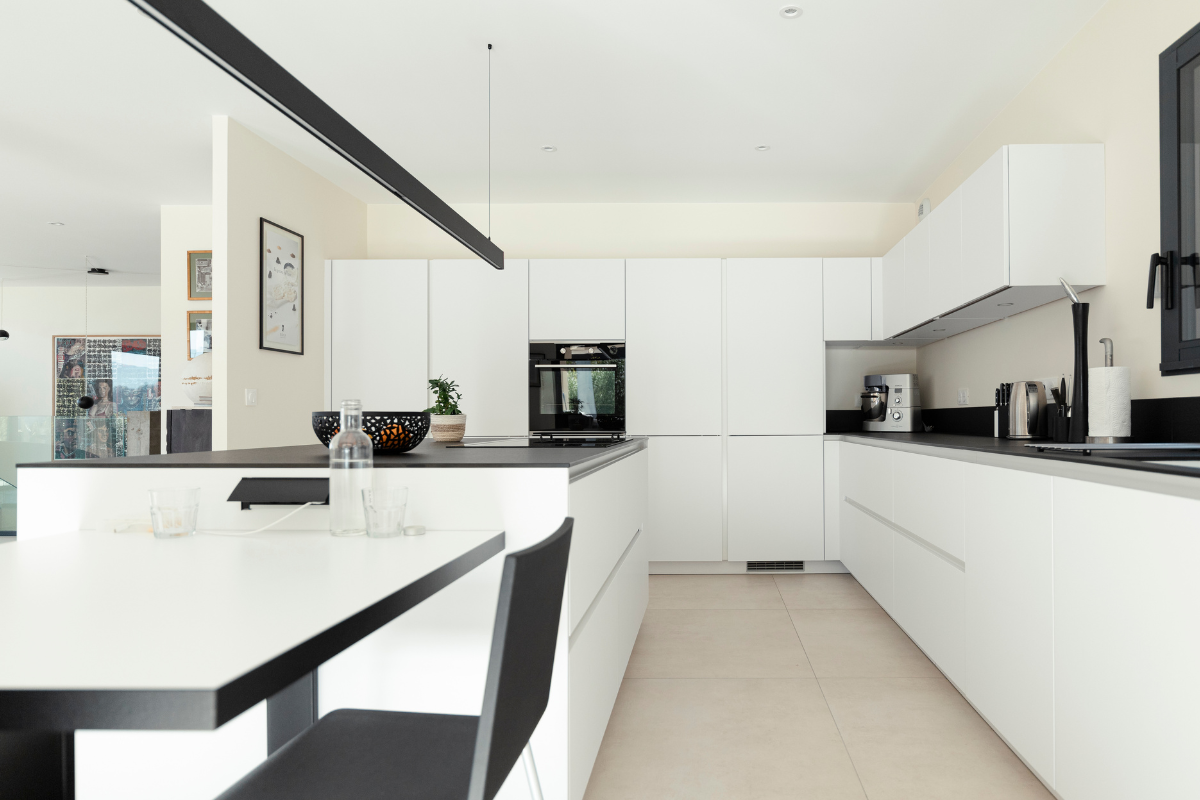 Cuisine moderne blanc et noir avec îlot dans le cadre d'une construction de maisons individuelles en Savoie.